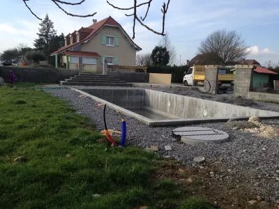 Bassin de piscine en béton en cours de construction avec réseaux techniques visibles
