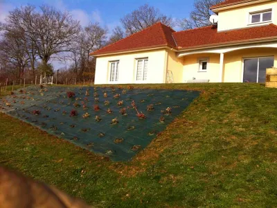 Talus paysager en cours de végétalisation avec toile de paillage et plantations