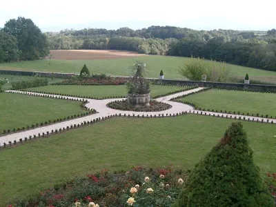 Jardin à la française structuré avec allées symétriques, pelouse et massif central