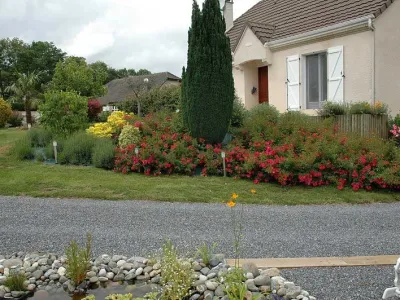 Massif fleuri et aménagement paysager soigné devant une maison avec allée gravillonnée