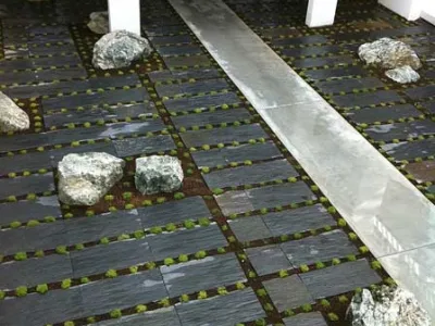 Détail de sol paysager intérieur avec dalles minérales, plantations et pierres décoratives