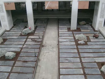 Jardin d’intérieur finalisé avec dalles minérales, pierres naturelles et circulation piétonne