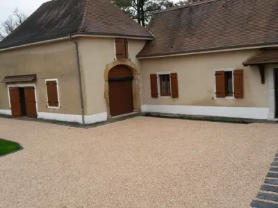 Cour aménagée avec gravier stabilisé et cheminement structuré devant une maison