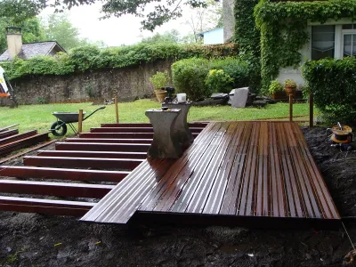 Pose des premières lames de terrasse bois sur structure porteuse, chantier extérieur à Oloron Sainte Marie