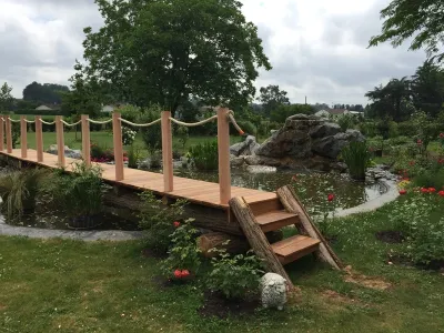 Passerelle en bois avec garde-corps traversant un bassin paysager naturel
