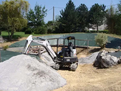 Chantier de rénovation de bassin naturel avec engins et préparation du sol