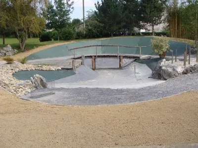 Bassin naturel en cours de rénovation avec passerelle bois et préparation des berges
