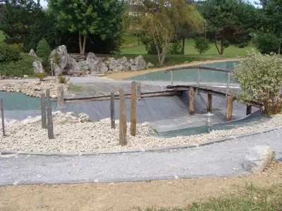 Aménagement minéral autour d’un bassin naturel avec passerelle et graviers décoratifs