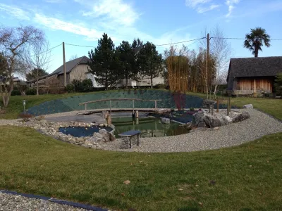 Bassin naturel finalisé à Féas avec eau, roches naturelles et aménagement paysager harmonieux